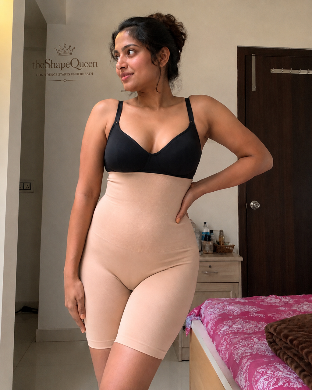 Woman wearing a black bra and beige shapewear in a room.